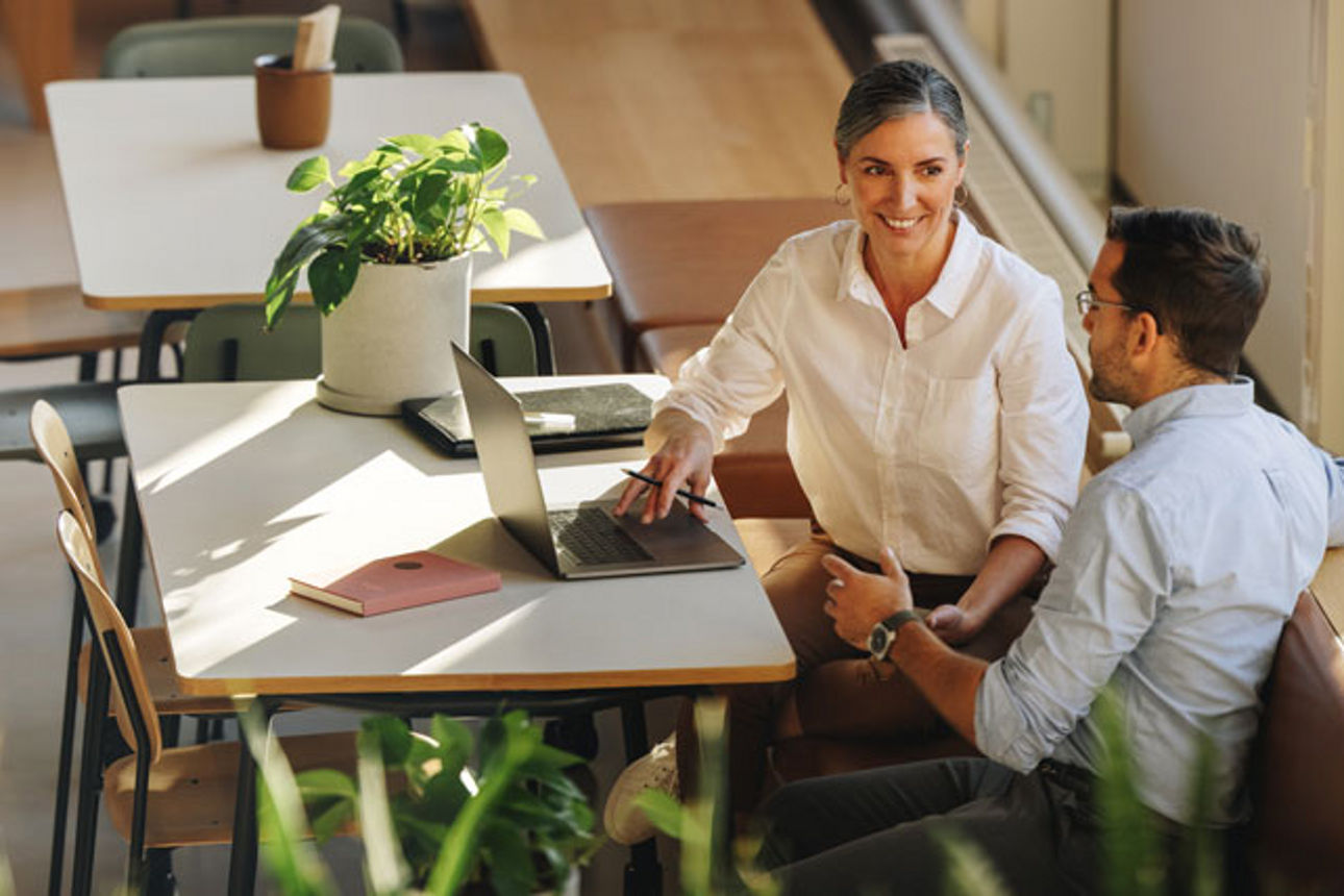 Zwei Personen sitzen im Büro und unterhalten sich