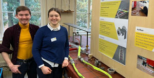 Zeigt zwei Frauen neben einer Infotafel