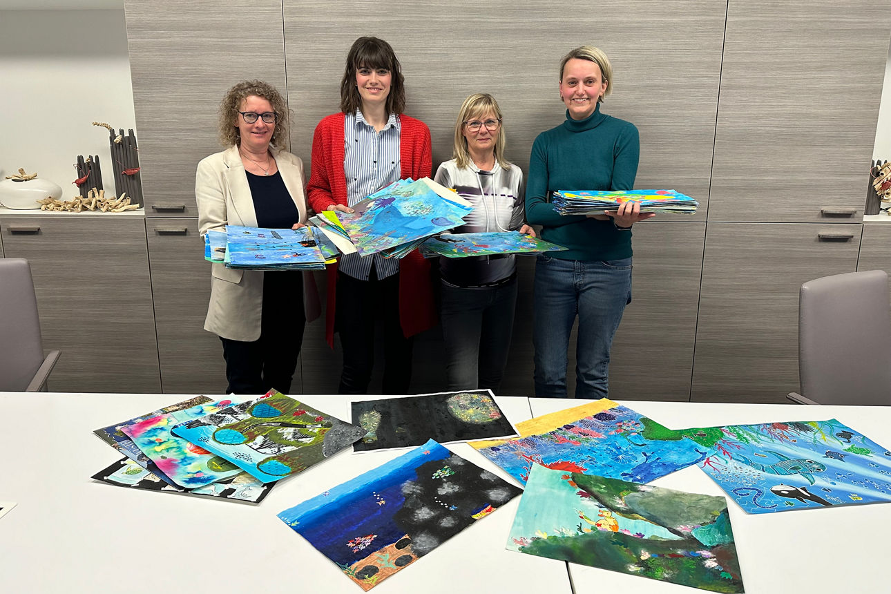 4 Frauen präsentieren in einem Besprechungsraum viele bunte Kinderbilder mit Meeres- und Unterwassermotiven