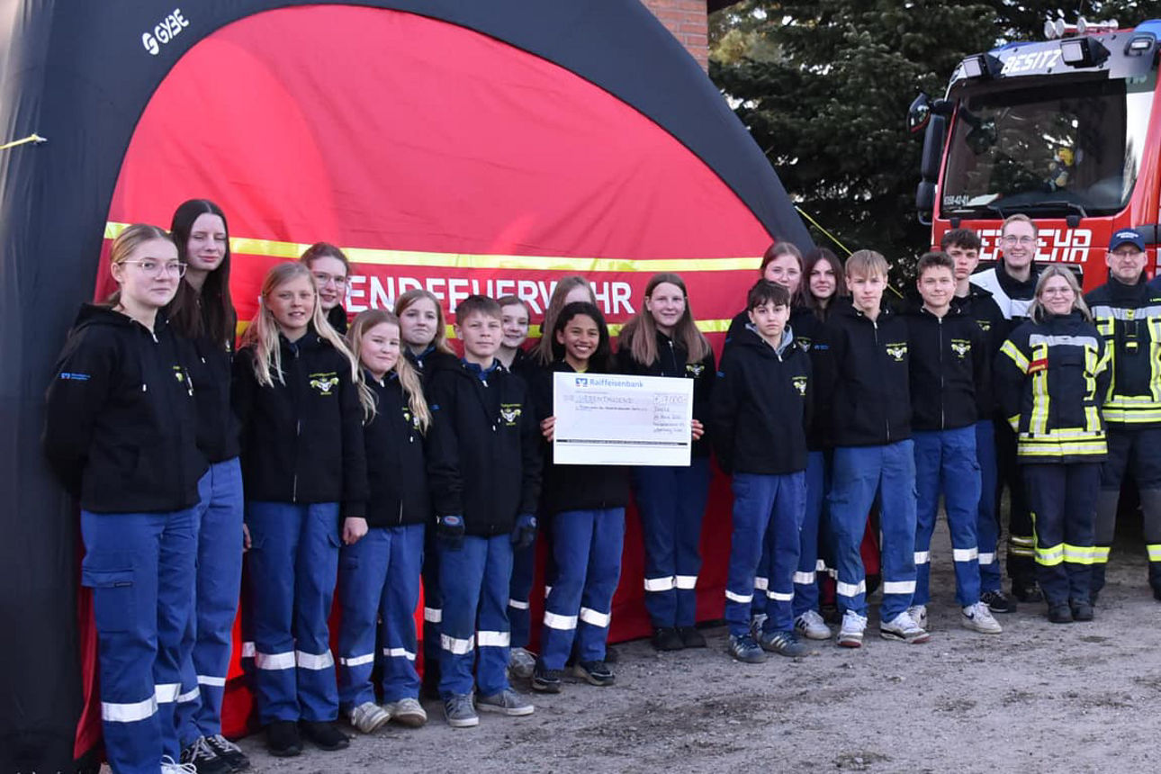 Mitglieder der Jugendfeuerwehr Besitz und Herr Göthling (Vorstand der Raiffeisenbank eG) stehen vor dem Schnelleinsatzzelt