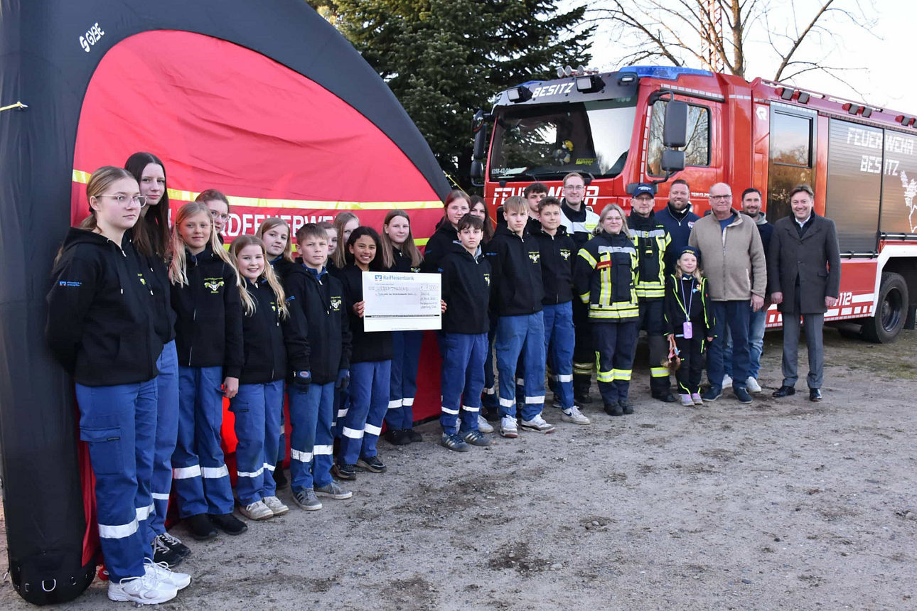 Mitglieder der Jugendfeuerwehr Besitz und Herr Göthling (Vorstand der Raiffeisenbank eG) stehen vor dem Schnelleinsatzzelt