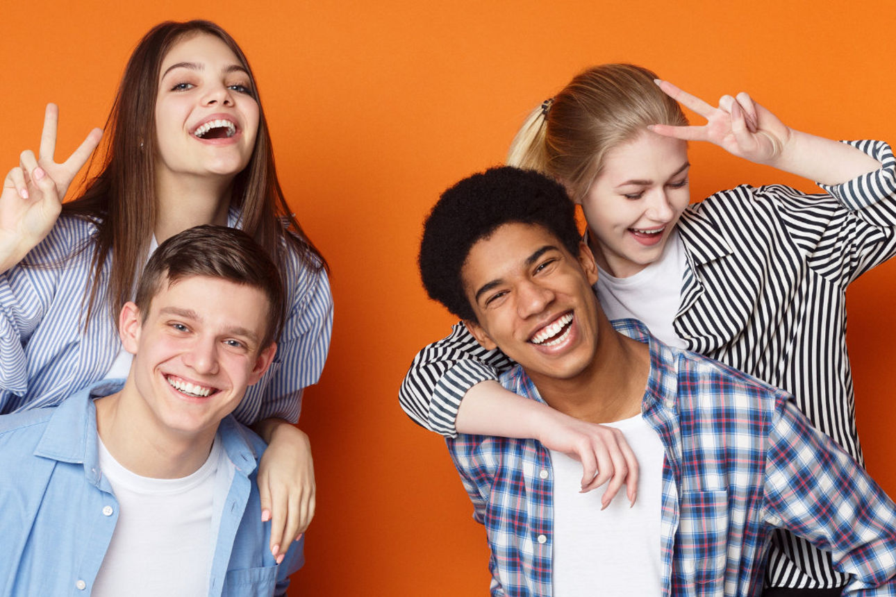 Vier lachende Jugendliche stehen nebeneinander.