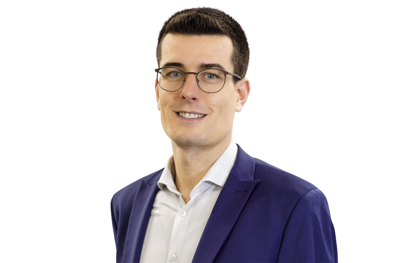 Portraitbild eines Mannes, mit einem blauen Anzug und einem weißen Hemd.