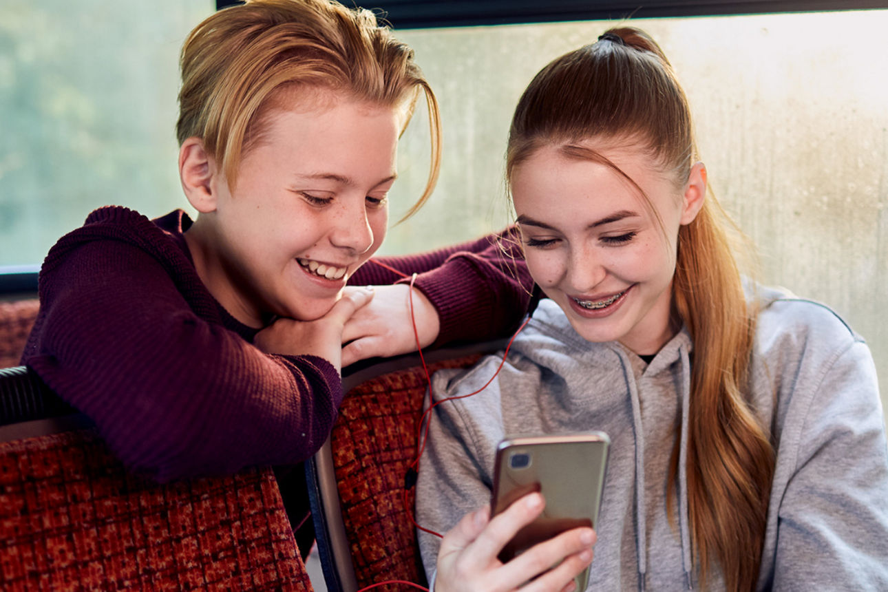 Zwei Kinder schauen in ein Smartphone.