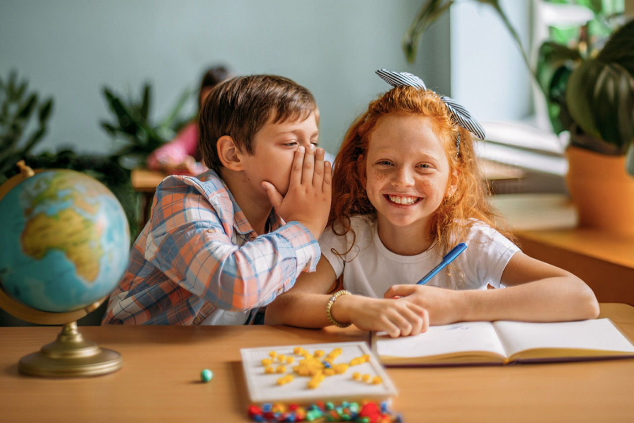 Zwei Kinder nebeneinander auf der Schulbank