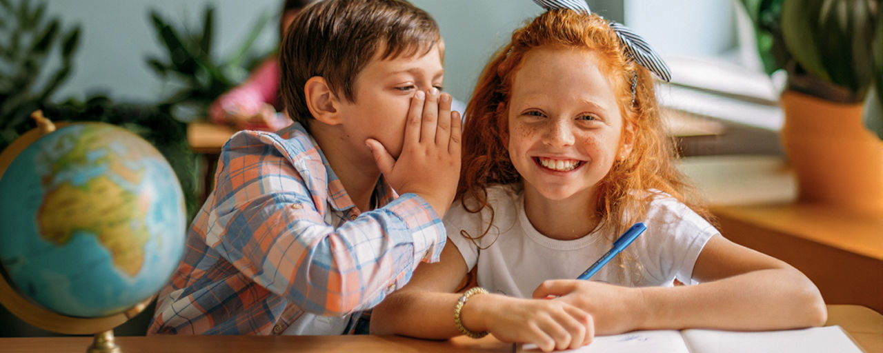 Zwei Kinder nebeneinander auf der Schulbank