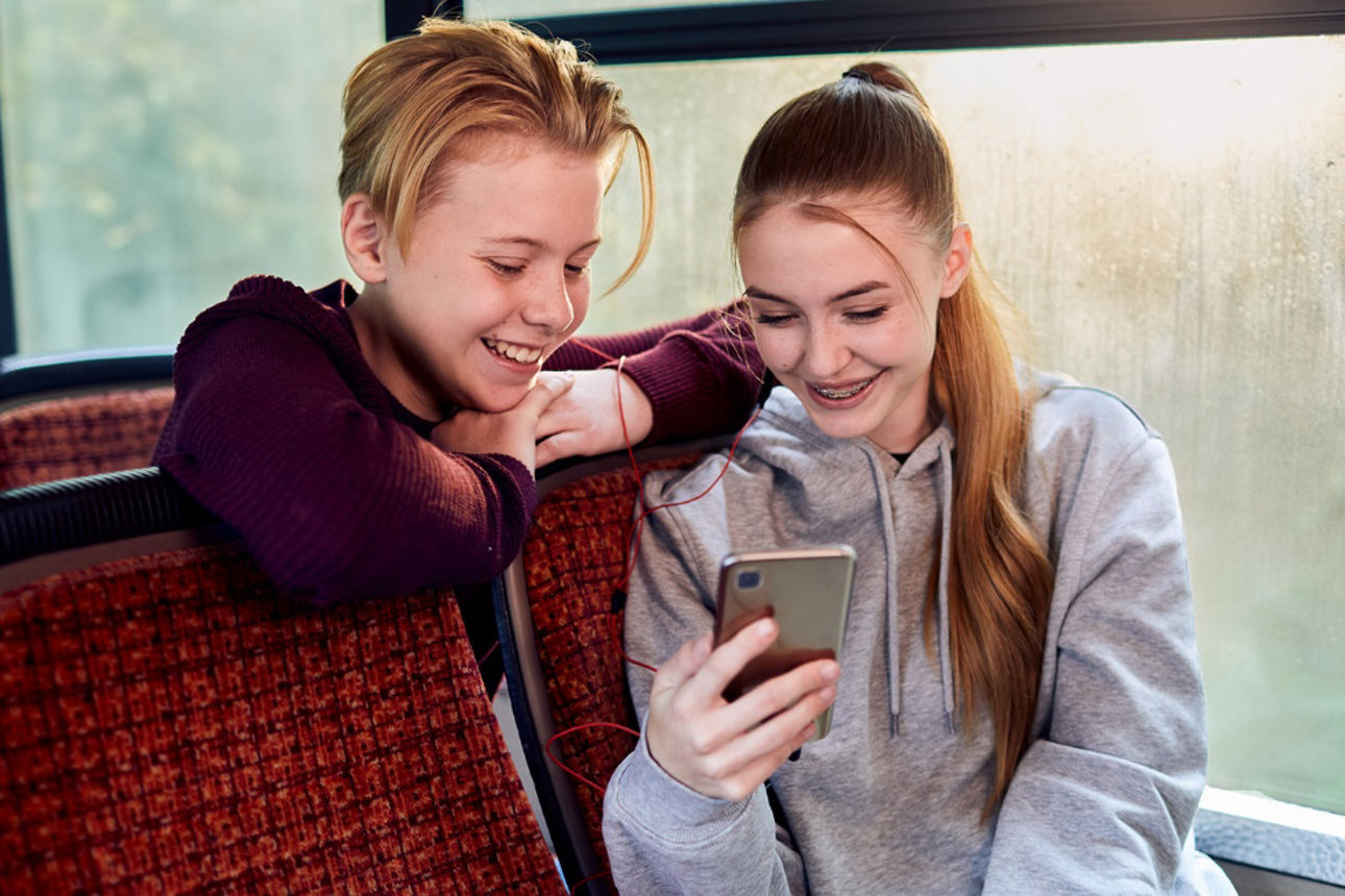 Zwei Kinder schauen in ein Smartphone.