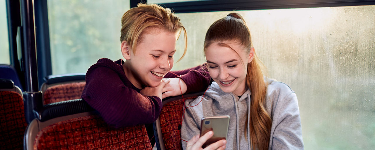 Zwei Kinder schauen in ein Smartphone.