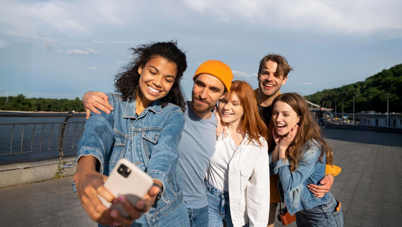 Bild von jungen Leuten unter blauem Himmel, die ein Selfie von sich machen.