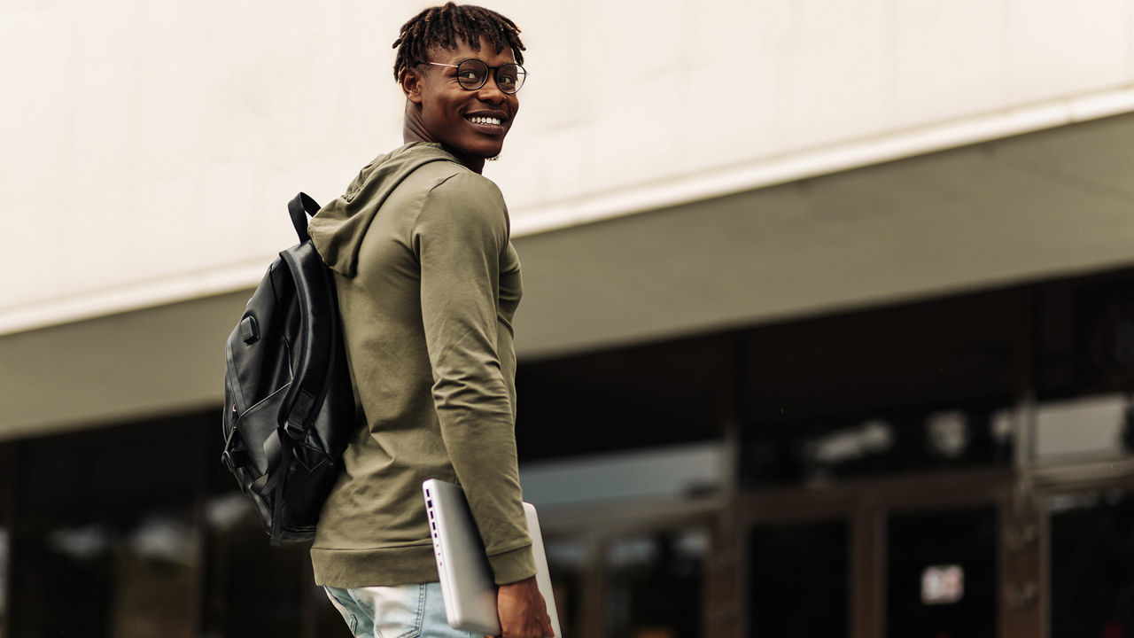 Student mit Rucksack, die über die Schulter schaut
