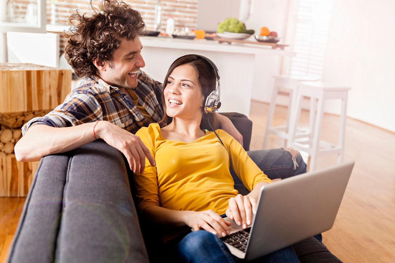 Ein Pärchen sitzt vor Ihrem Laptop und schaut sich die aktuellen Immobilienangebote an