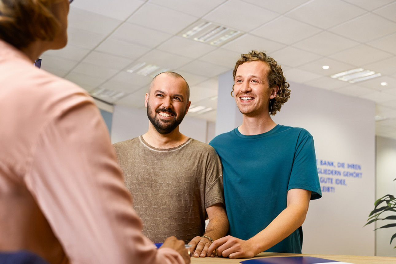 Zwei Jugendliche sprechen in einer Bankfiliale mit einer Beraterin