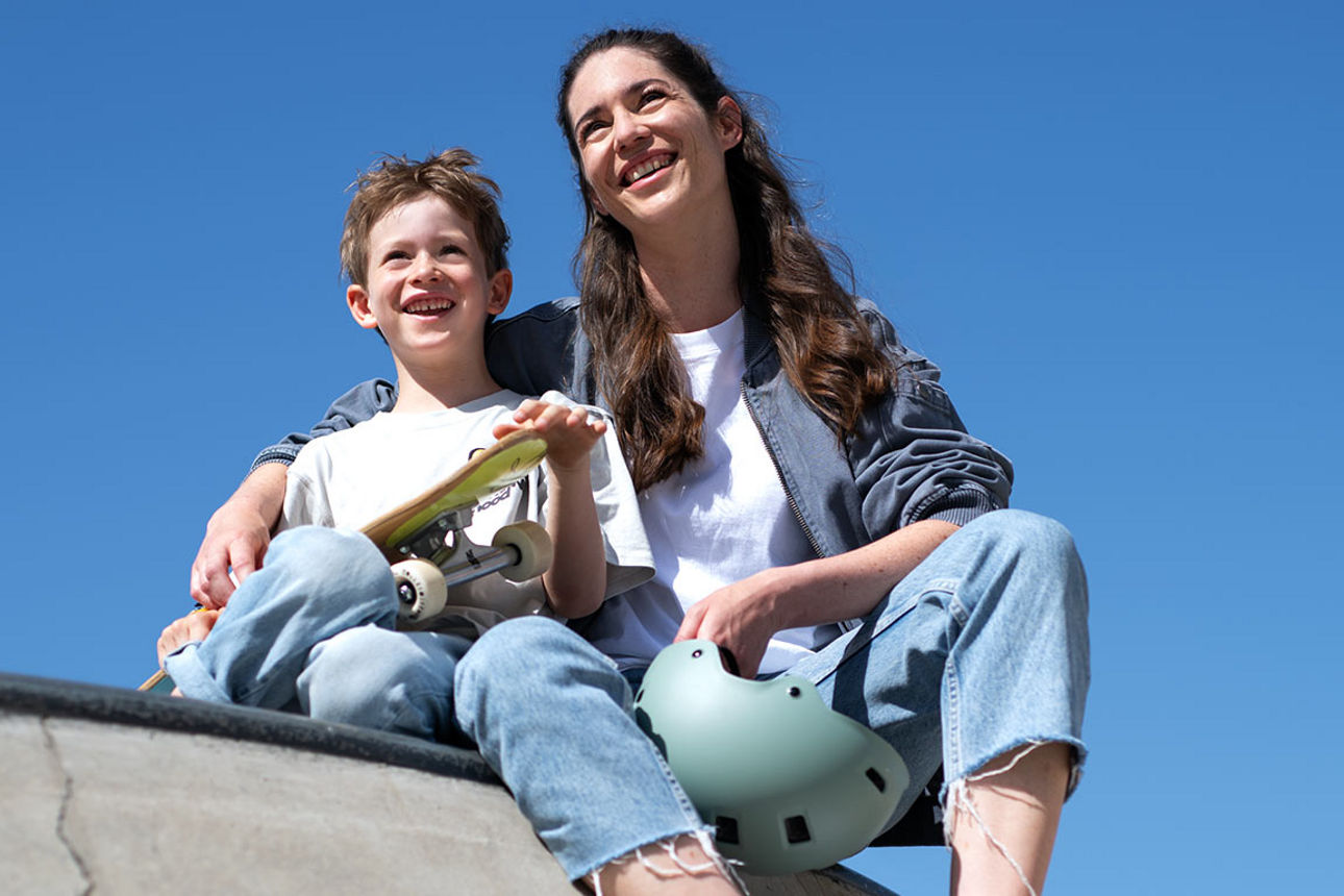 Ein Junge mit Skateboard sitzt neben seiner Mutter