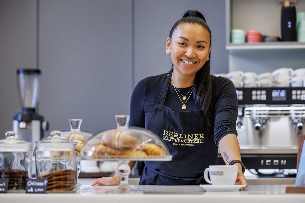 Barista steht an Tresen und serviert einen Kaffee