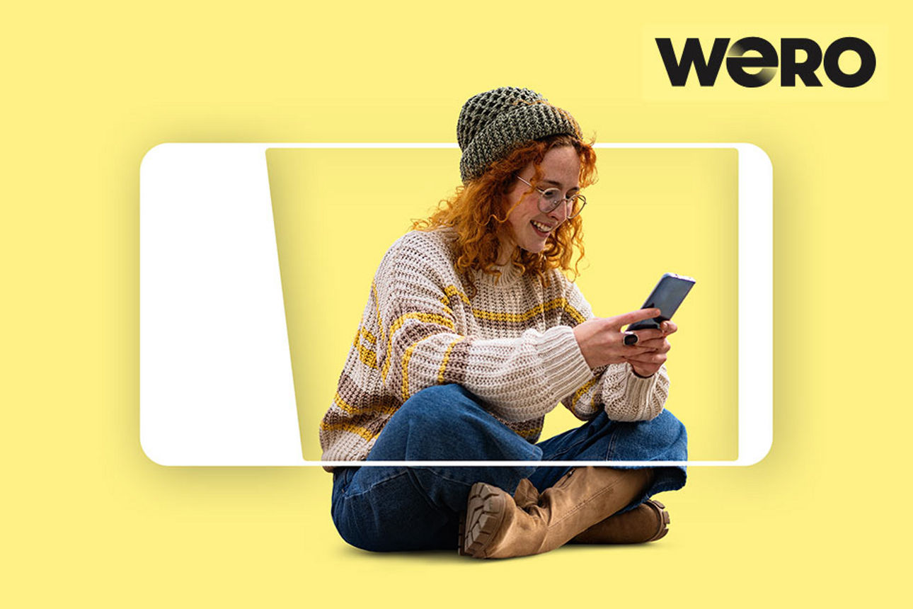 Frau mit Mütze sitzt im Schneidersitz und schaut auf ihr Mobiltelefon