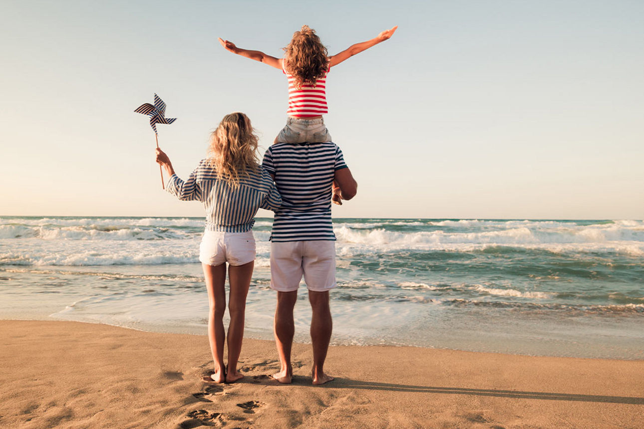 Familie steht im Sand am Meer