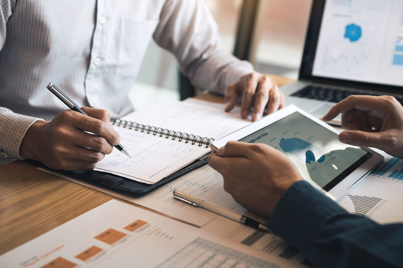Two business partnership coworkers discussing a financial planning graph and company during a budget meeting in office room.