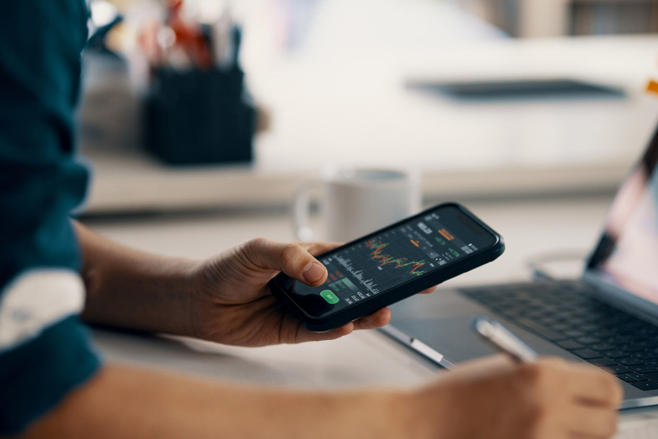 Eine Hand hält ein Smartphone mit Chart auf dem Display