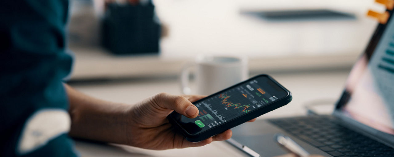 Eine Hand hält ein Smartphone mit Chart auf dem Display