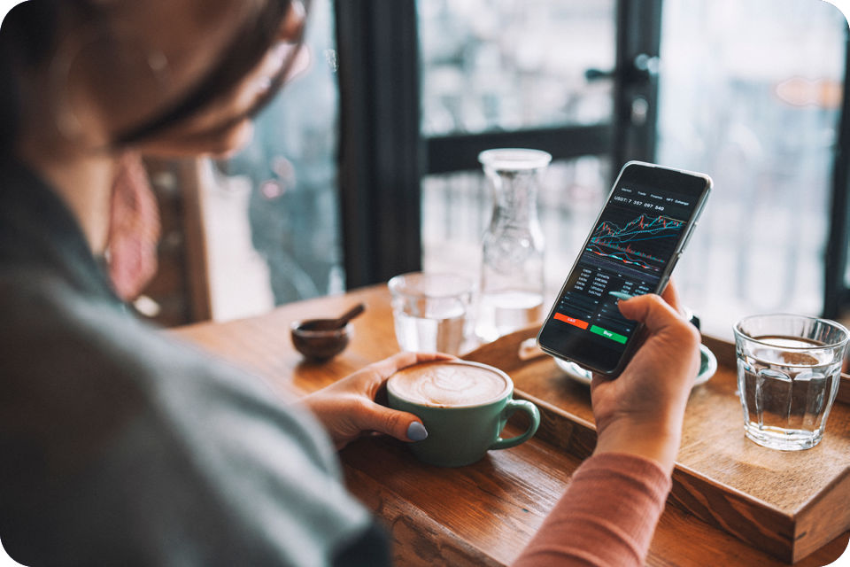 Trading-App auf Smartphone im Café