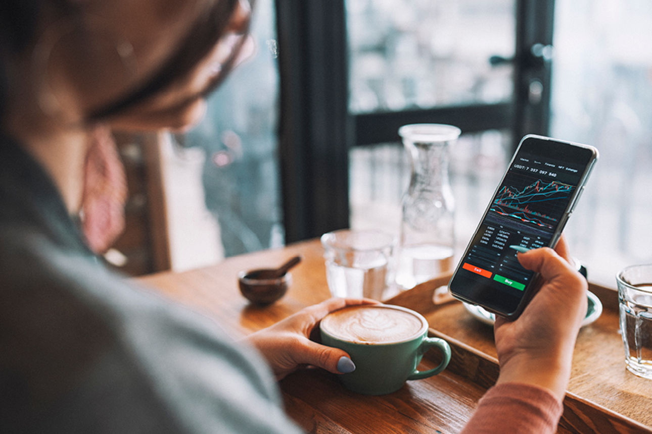 Trading-App auf Smartphone im Café