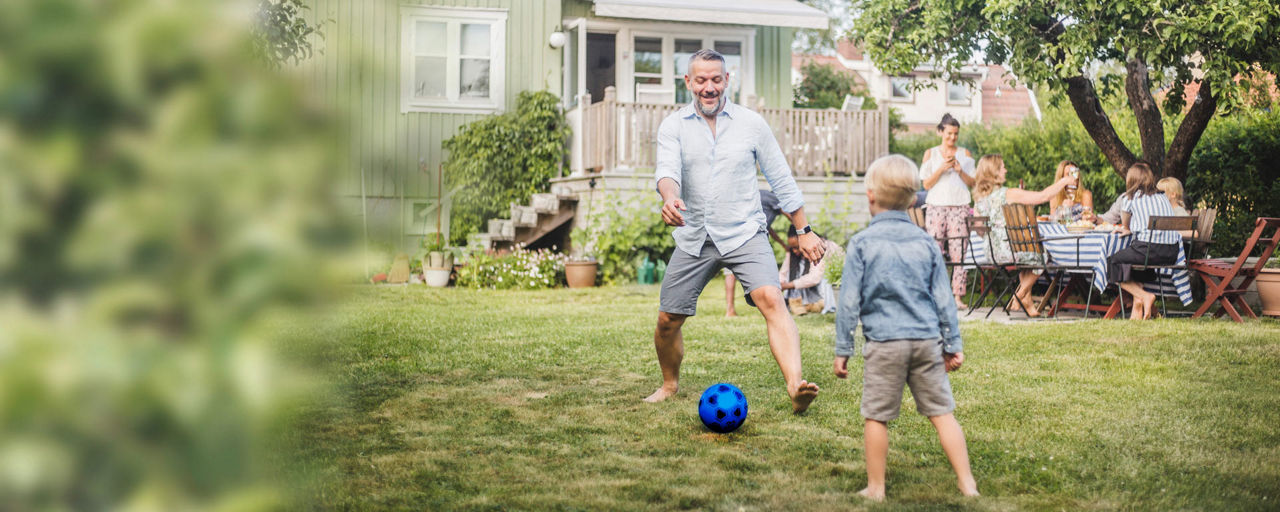Ein Mann und ein Kind spielen im Garten Fußball