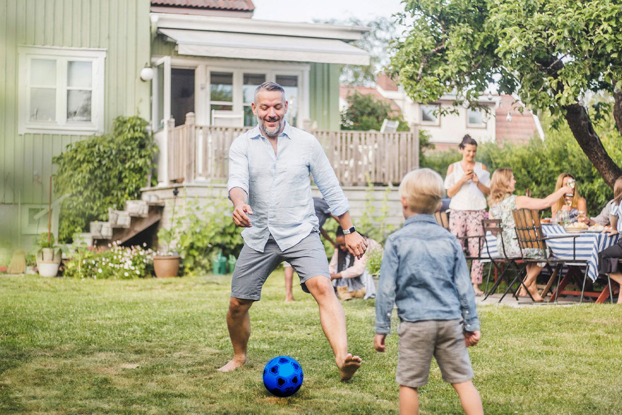 Ein Mann und ein Kind spielen im Garten Fußball