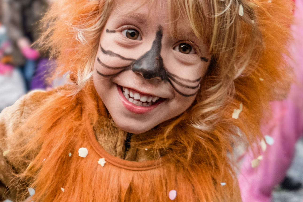 Ein Kind lächelt, als Löwe verkleidet, in die Kamera.