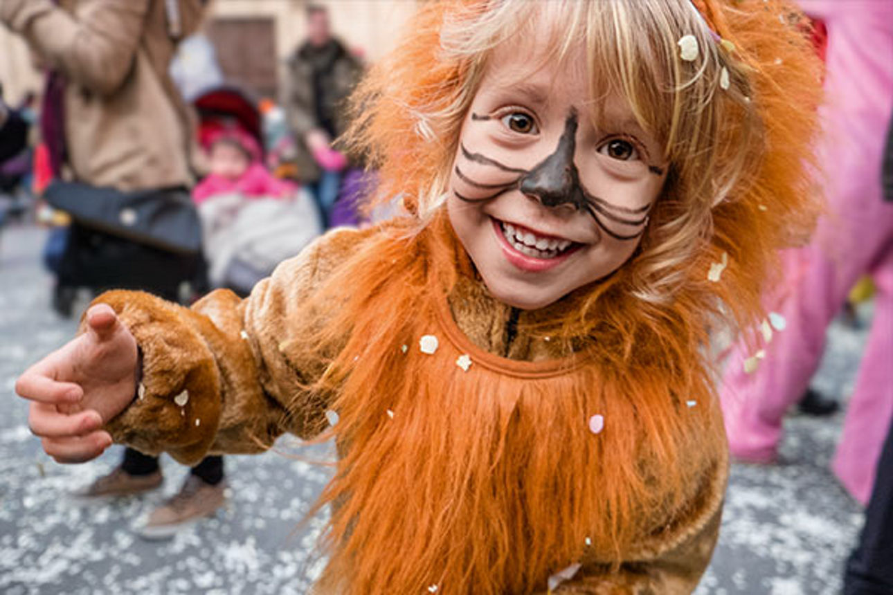 Lachendes Kind in einem Löwenkostüm beim Straßenfasching
