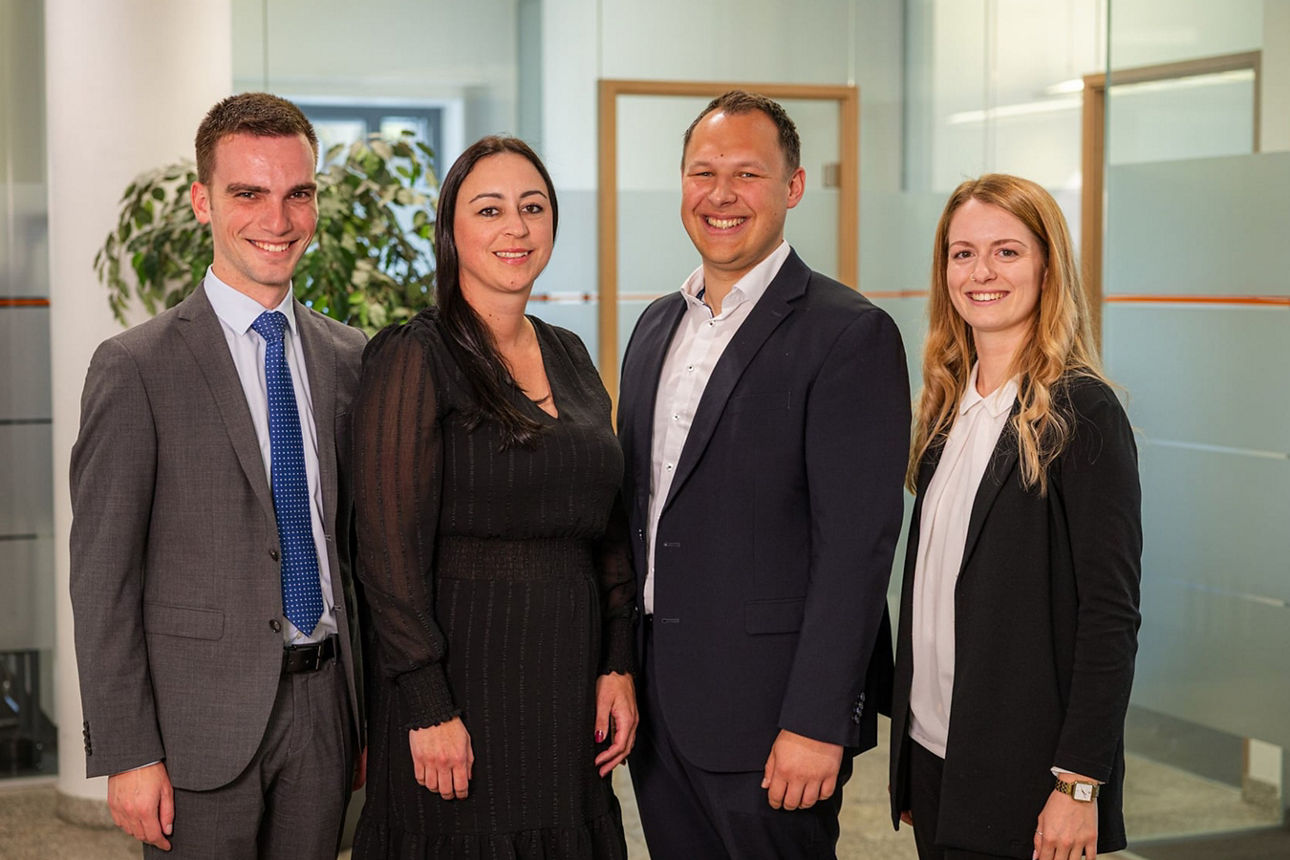 Gruppe von vier Mitarbeitern die freundlich in die Kamera schauen