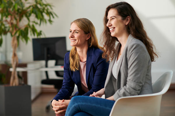 Zwei Frauen sitzen nebeneinander und lächeln