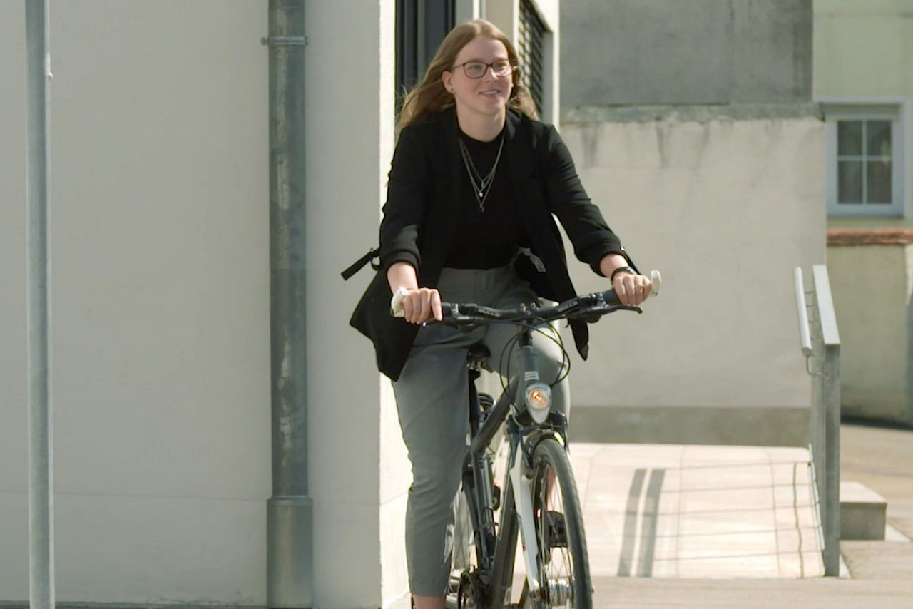 Junge Frau fährt auf dem Rad eine Straße entlang