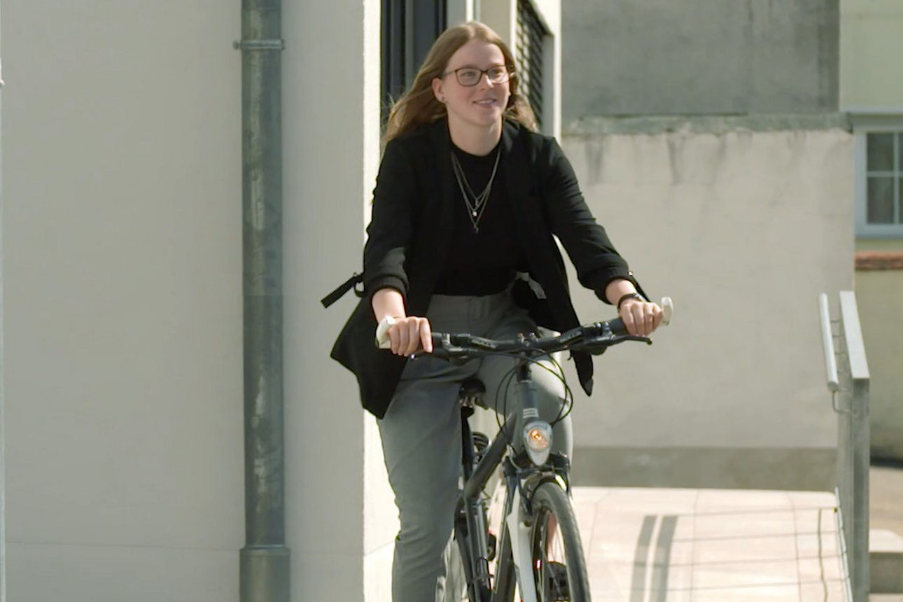 Junge Frau fährt auf dem Rad eine Straße entlang