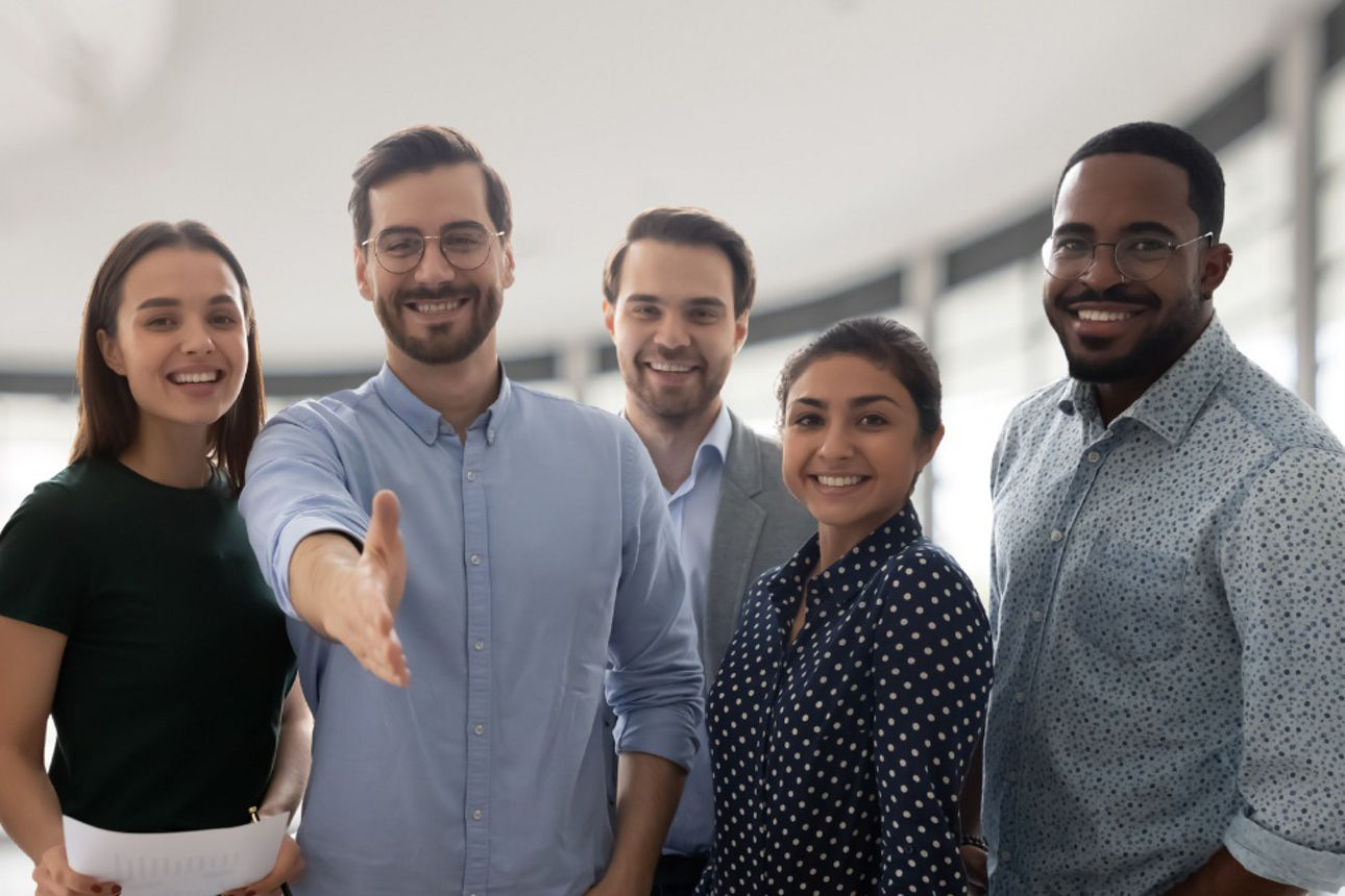 Fünf zukünftige Kolleginnen und Kollegen. Ein junger Mann reicht die Hand zur Begrüßung.