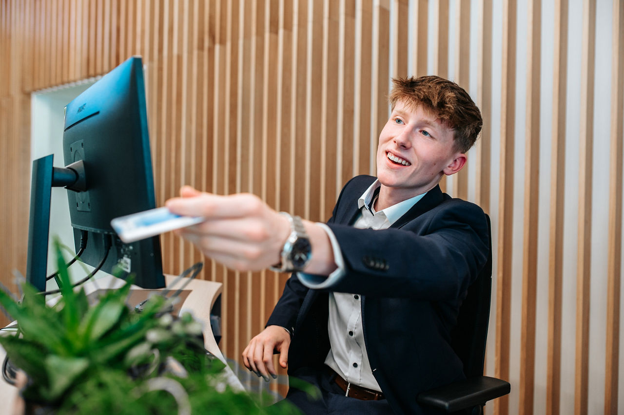 Eine junger Mann reicht lächelnd die girocard über den Serviceschalter