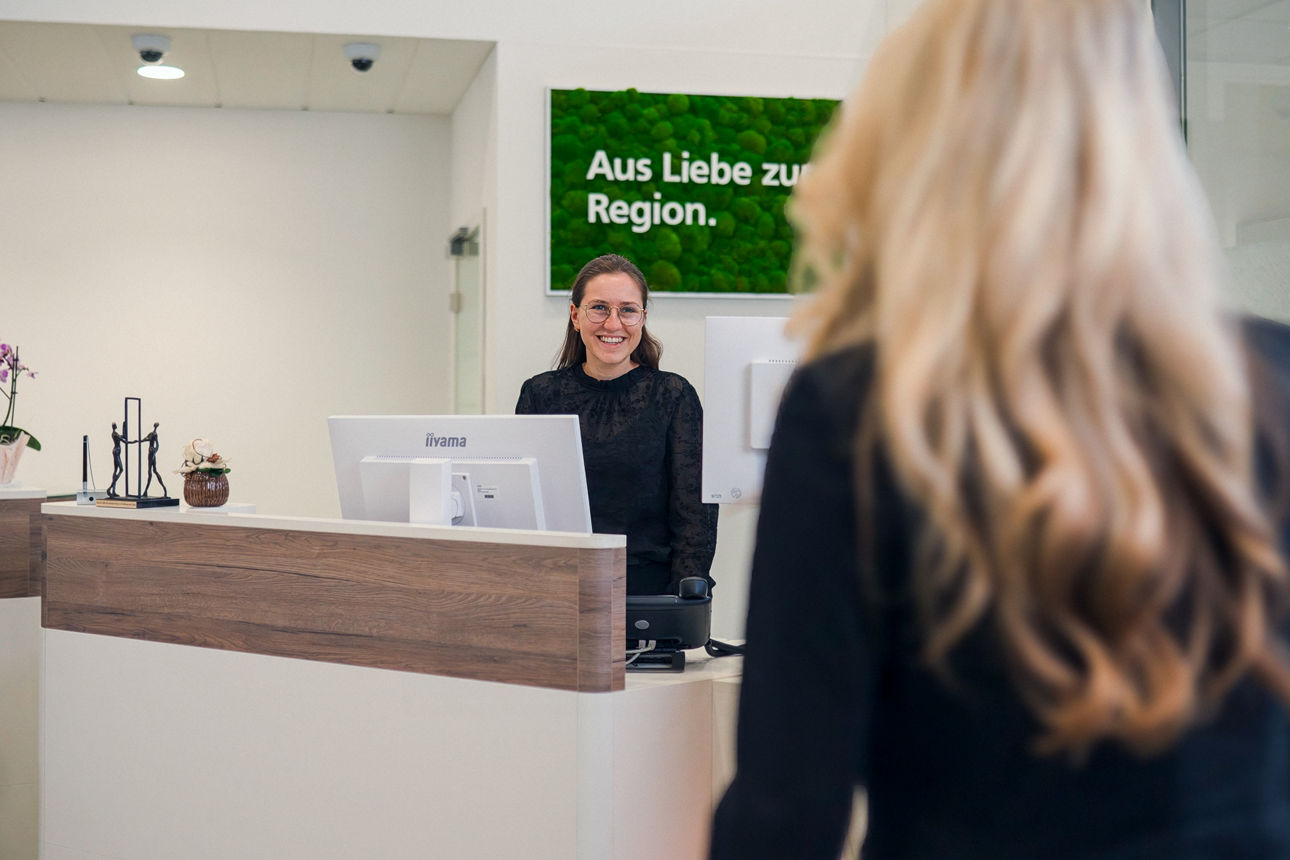 Eine junge Frau sitzt hinter dem Service-Schalter