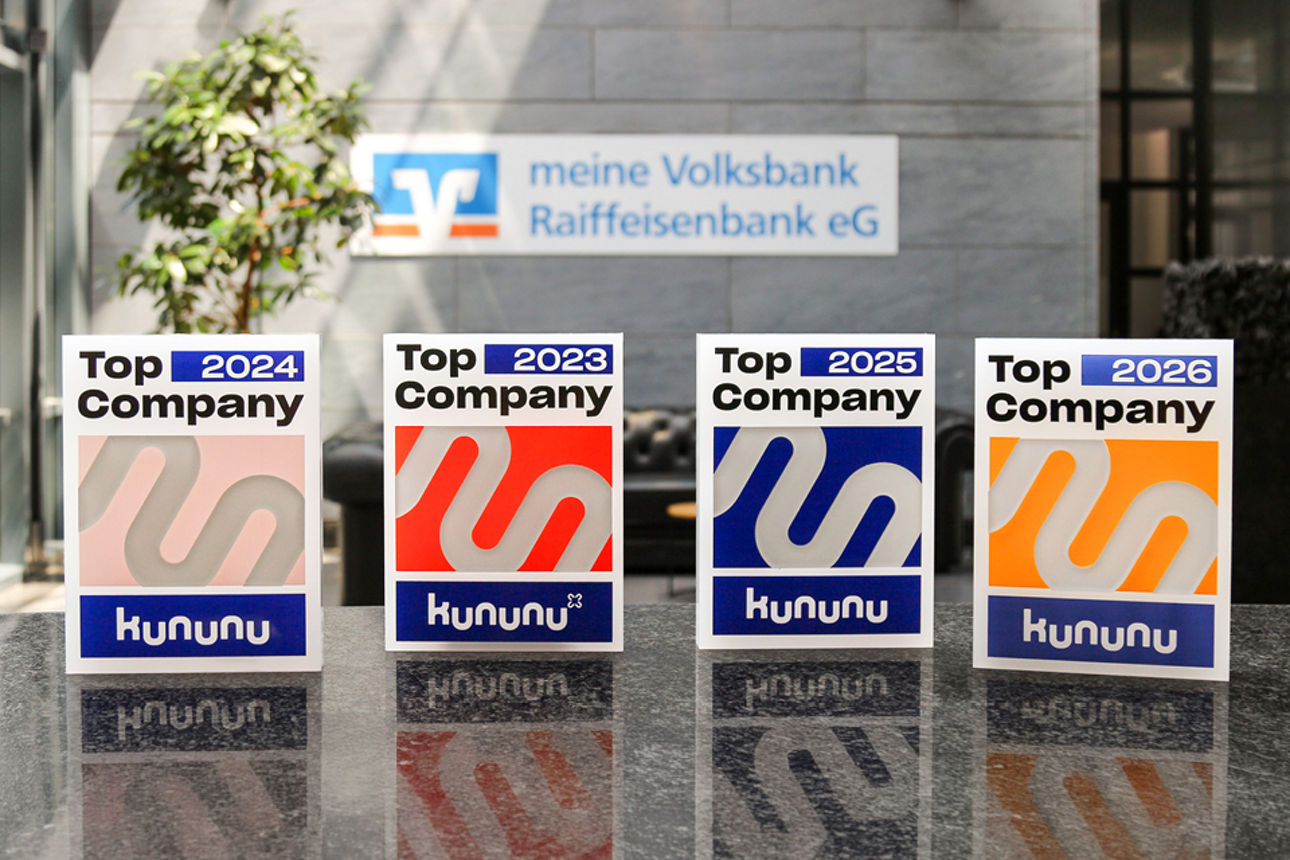 Kununu-Auszeichnungen als Top Company vor dem Unternehmenslogo der meine Volksbank Raiffeisenbank eG.