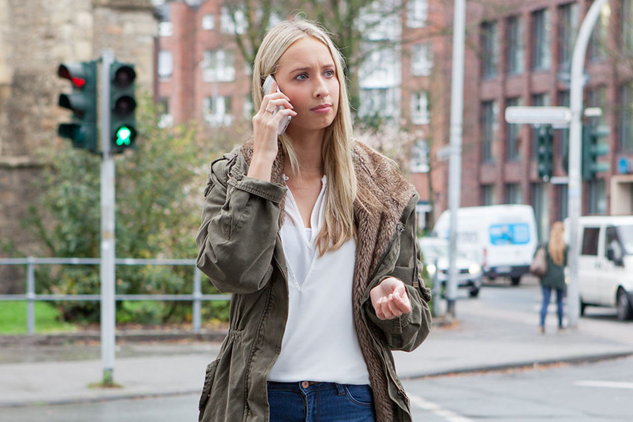 Frau mit einen Handy am ohr auf einer Straße