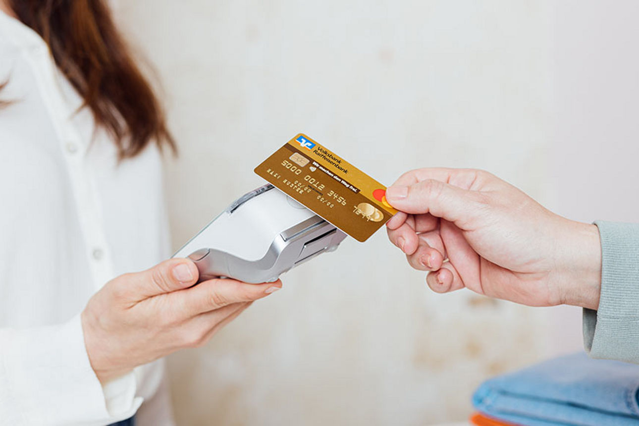 Kartenterminals bei der Münchner Bank eG Eine Hand hält einen goldene Kreditkarte an ein Kartenlesegerät