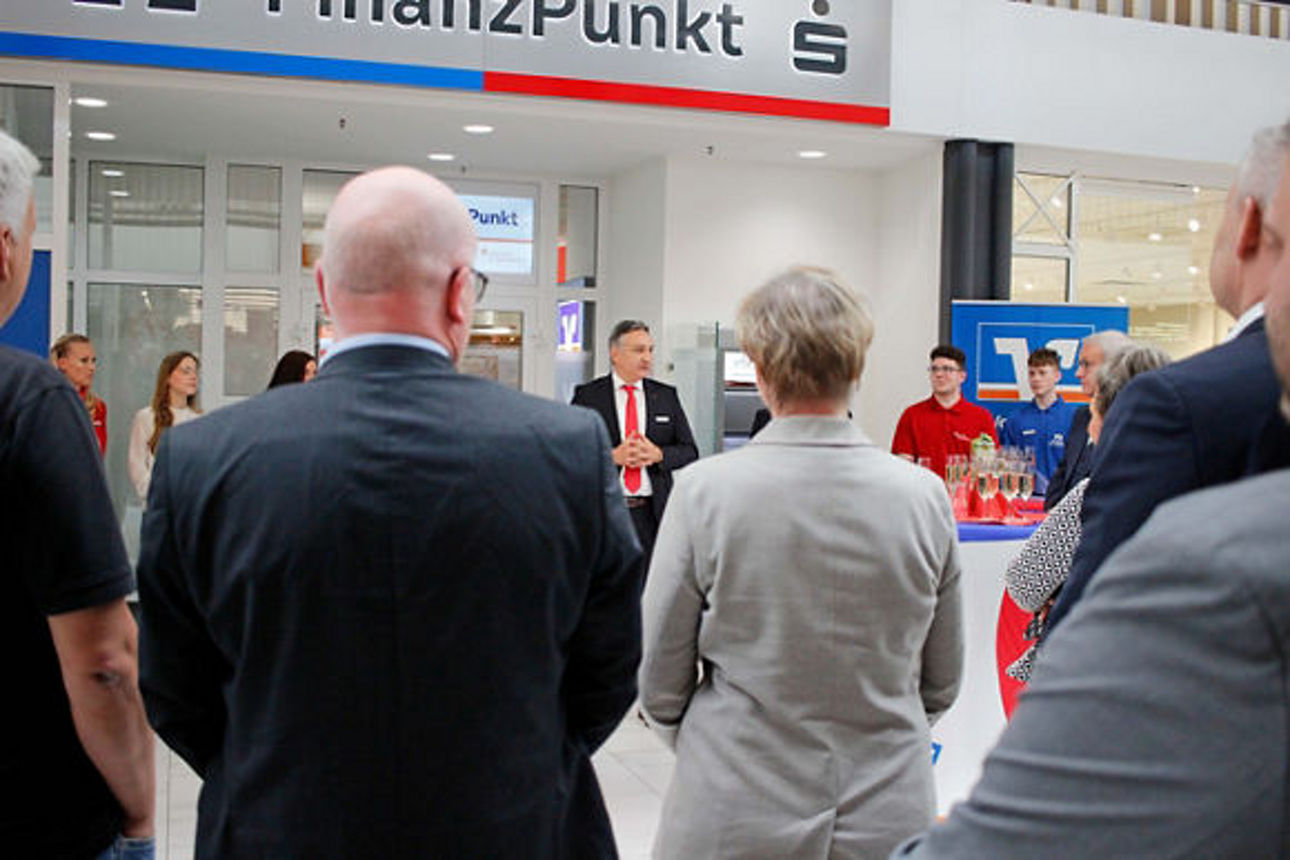 Mann mit roter Krawatte steht vor dem Finanzpunkt und hält eine Rede