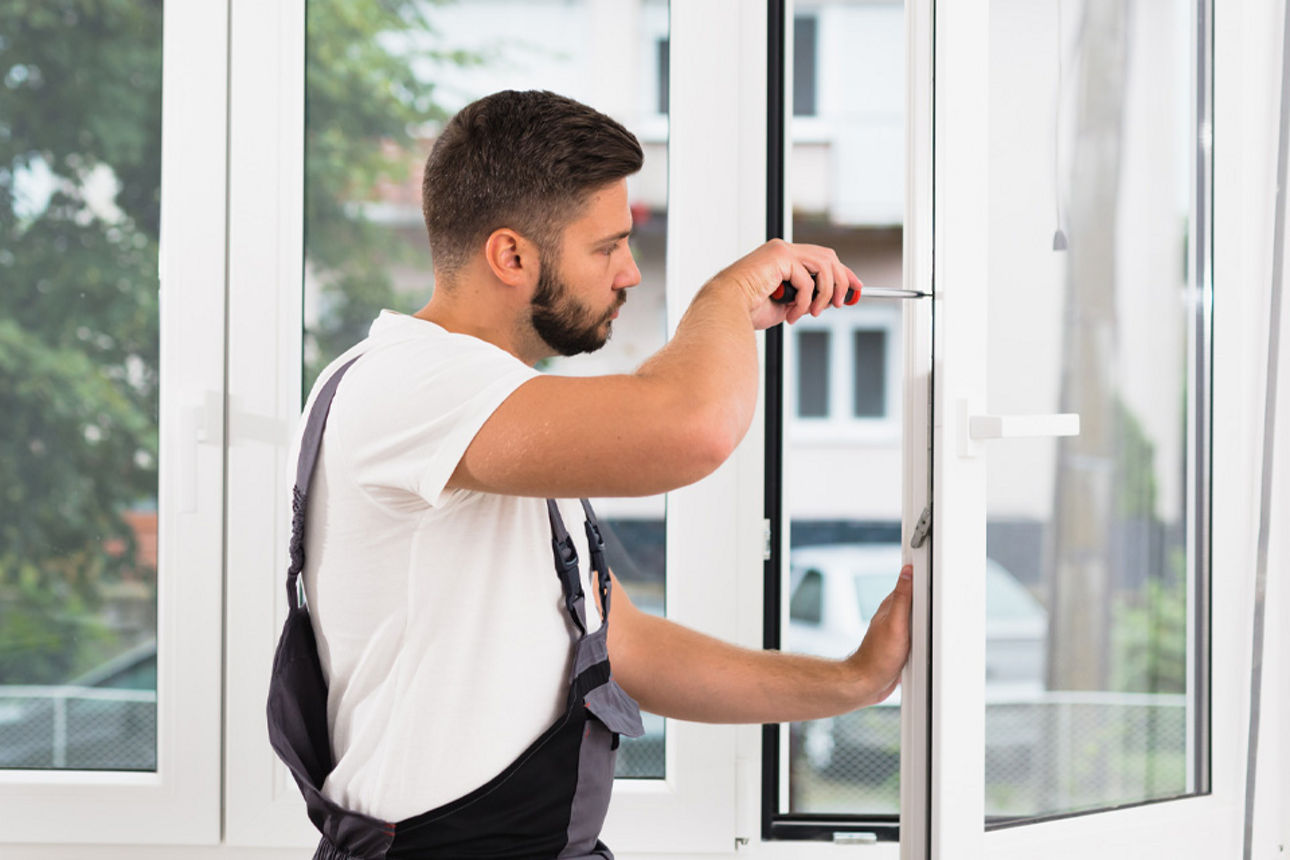 Handwerker schraubt an einem Fenster