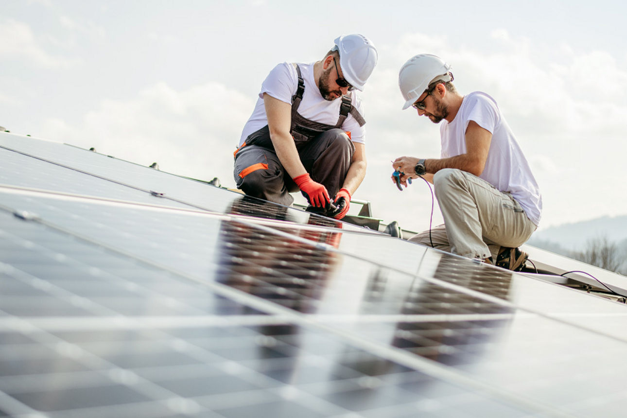 Zwei Handwerker montieren Solar-Paneele