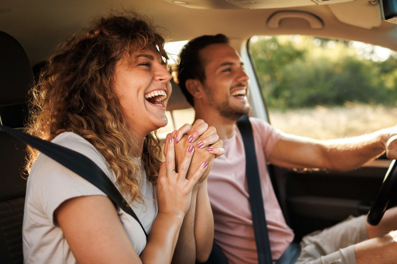 Person auf dem Beifahrersitz zeigt Daumen hoch, während eine andere Person das Auto fährt.
