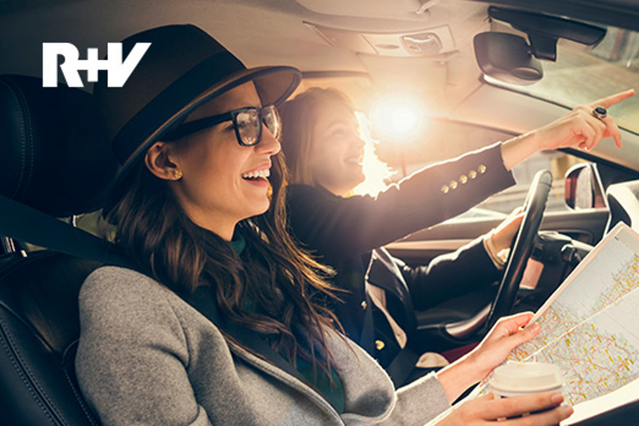 zwei Frauen sitzen in einem Auto und zeigen auf etwas außerhalb des Autos