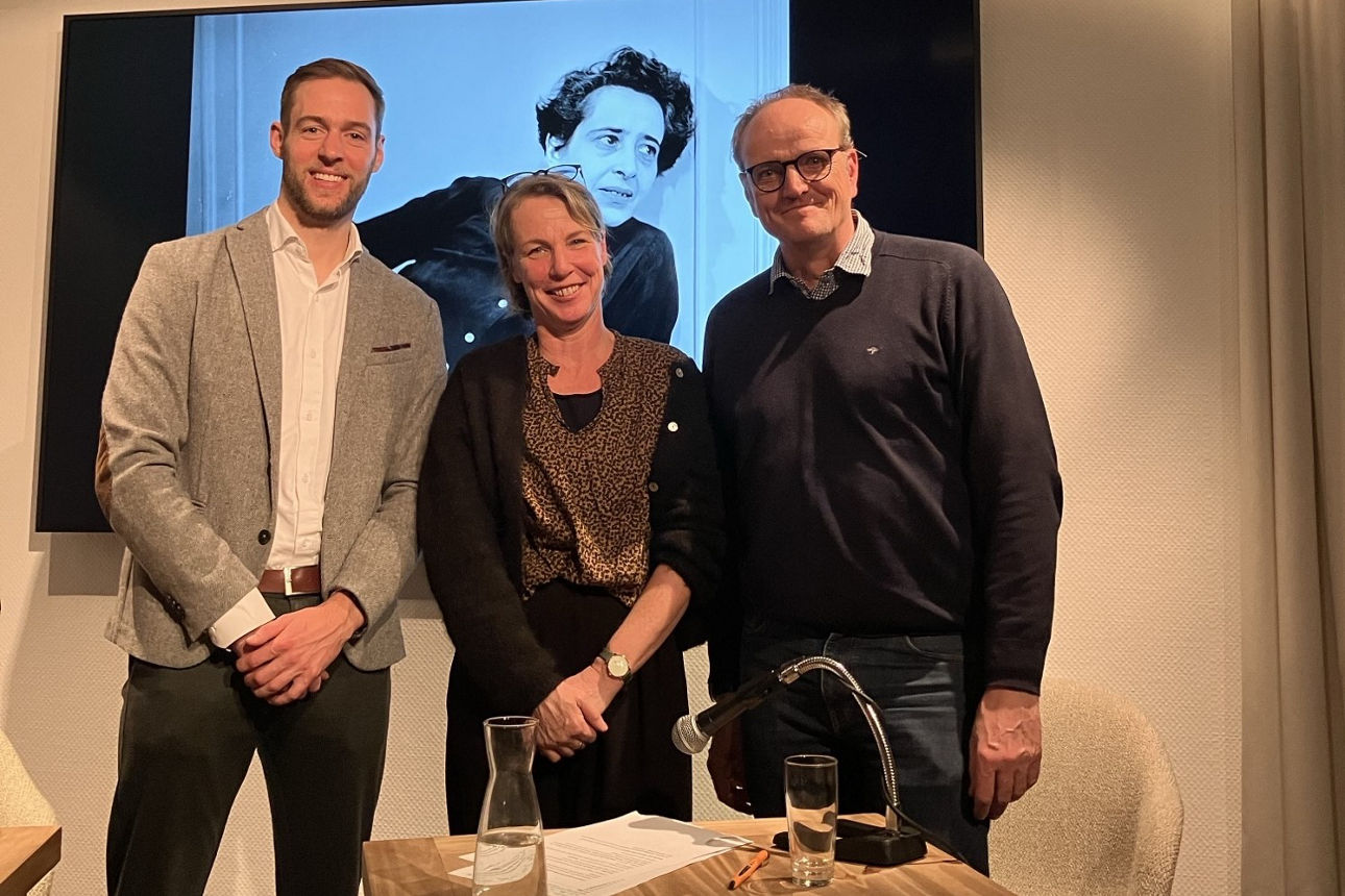 Zwei Männer und eine Frau stehen vor einer Leinwand 