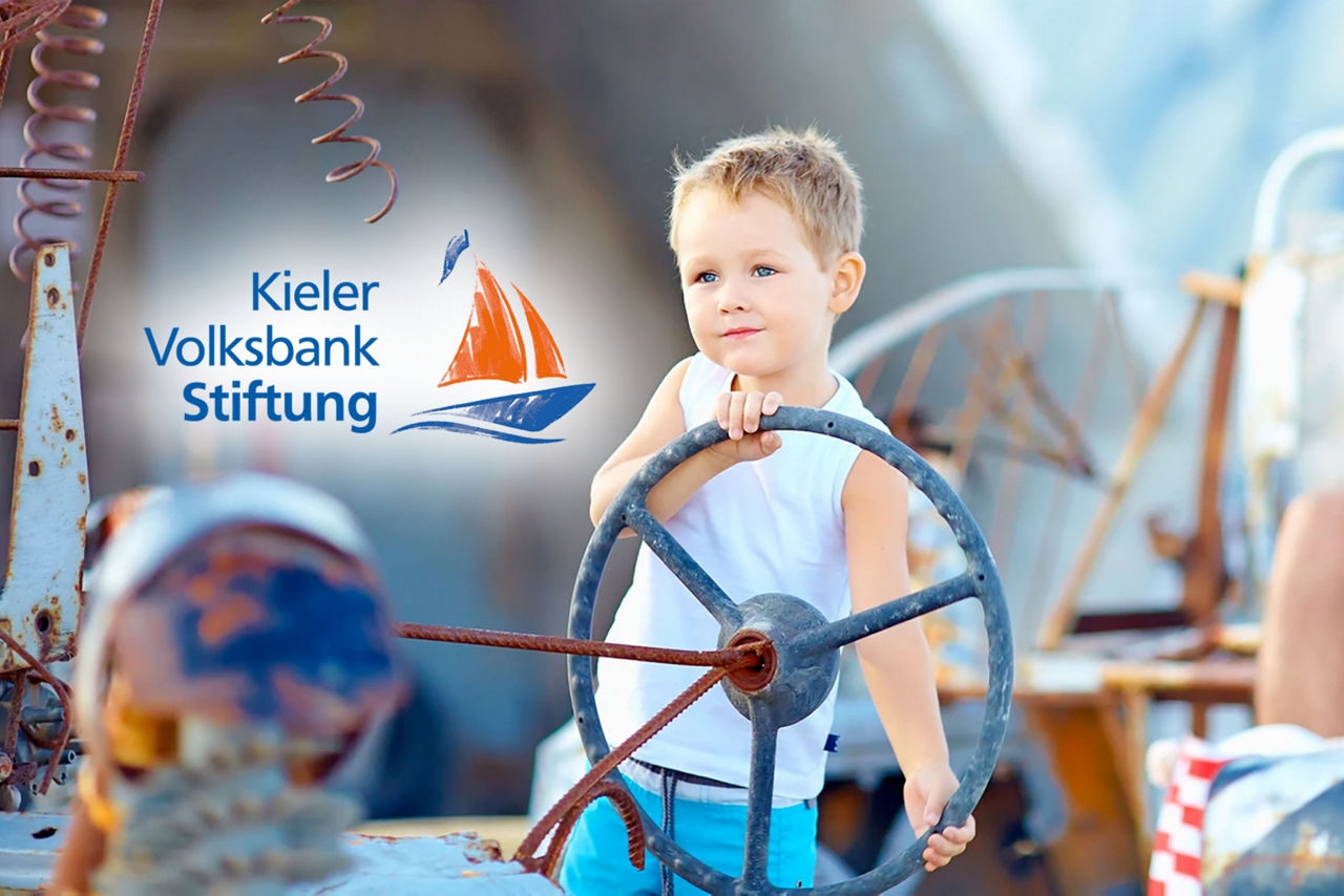 Junge am Steuer Boot mit Logo Kieler Volksbank-Stiftung