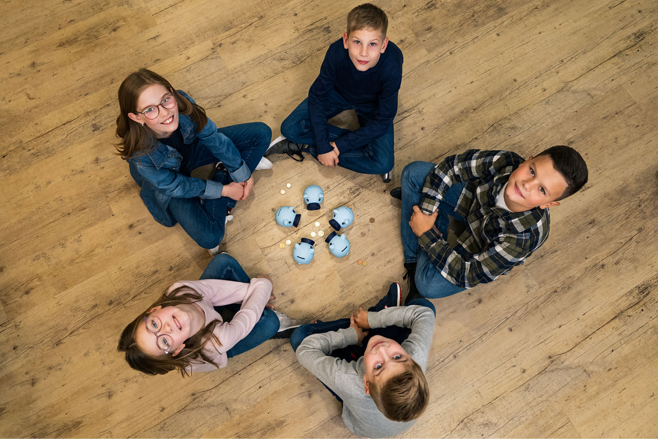 Kinder sitzen im Kreis um mehrere Steckdosen