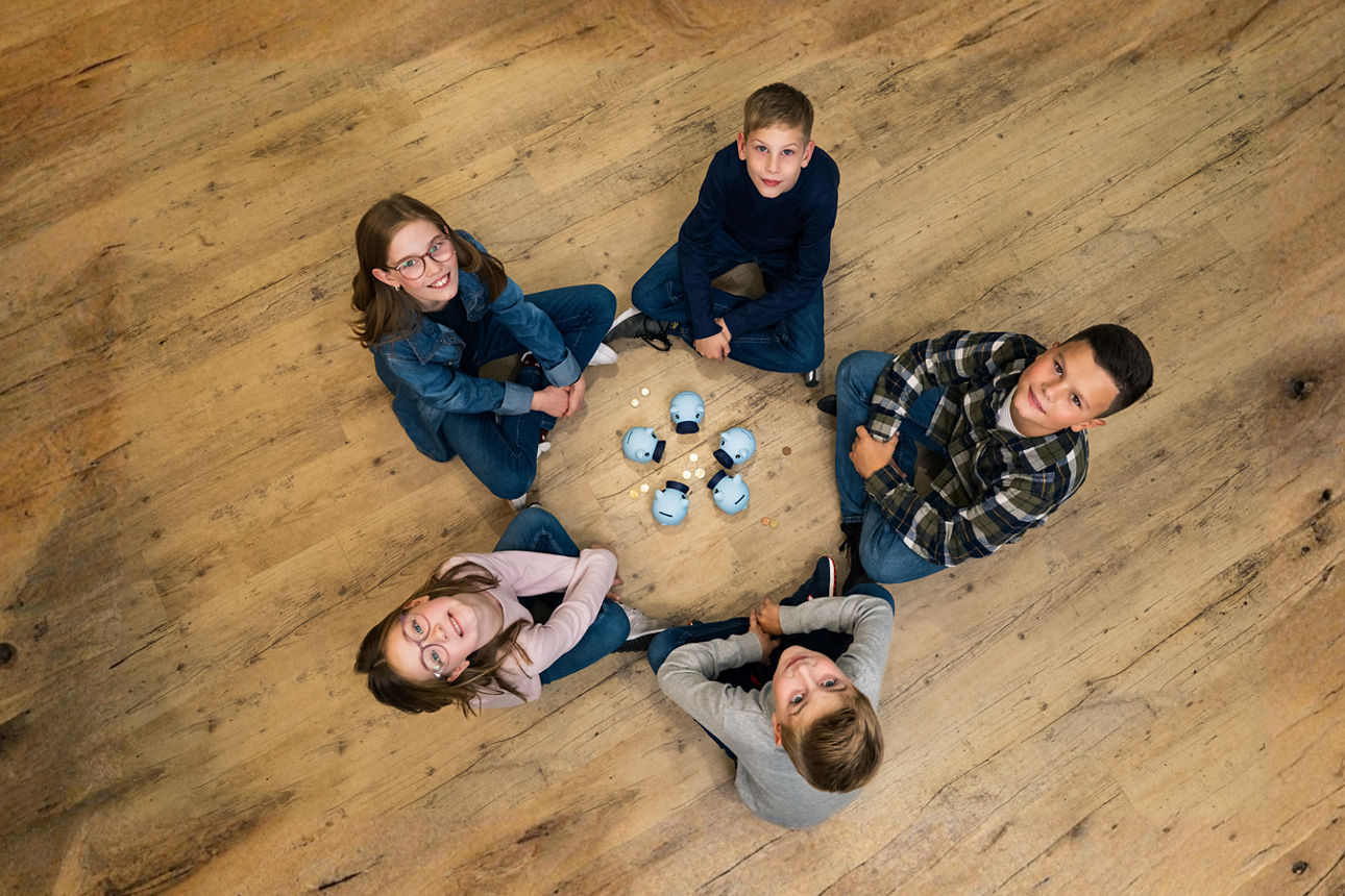 Kinder sitzen im Kreis um mehrere Steckdosen