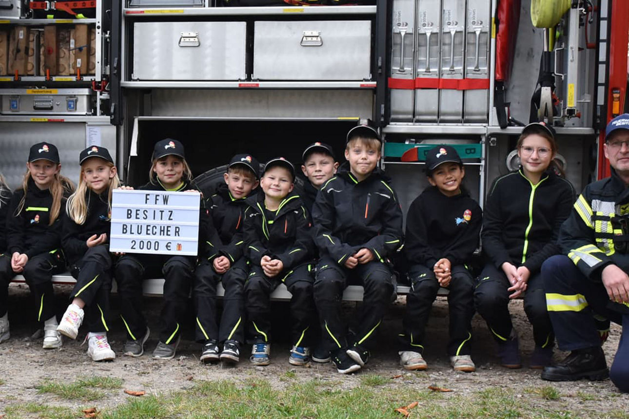 Mitglieder der Kinderfeuerwehr Besitz vor einem geöffnetem Feuerwehrauto