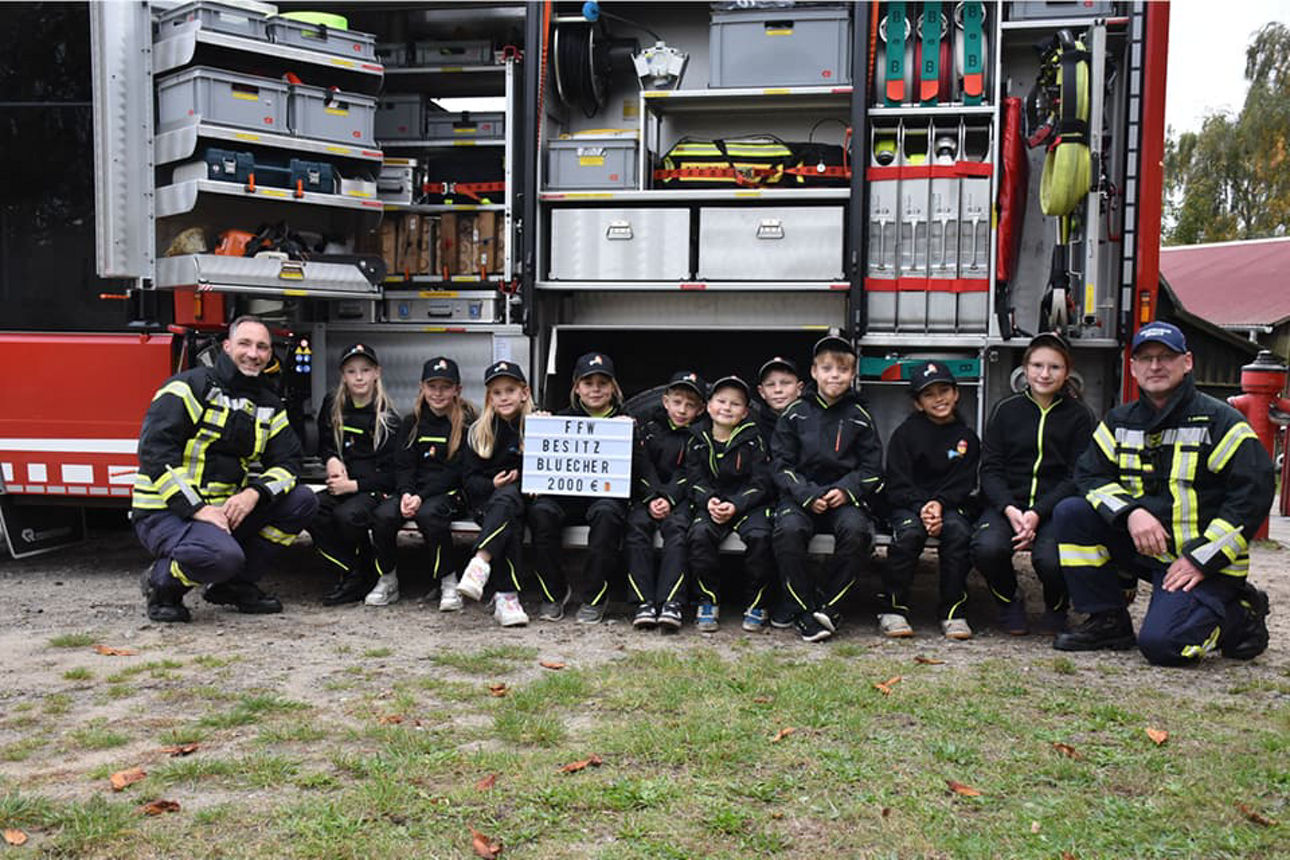 Mitglieder der Kinderfeuerwehr Besitz vor einem geöffnetem Feuerwehrauto